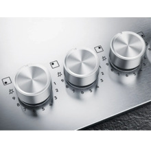 Close-up van drie zilverkleurige draaiknoppen van een kookplaat met temperatuurindicaties