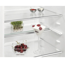 Koelkast met glazen planken en diverse voedingsmiddelen in schalen