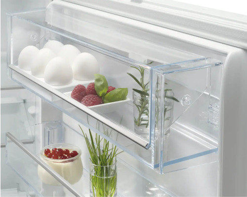 Interieur van een koelkast met eieren, frambozen, kruiden en yoghurt