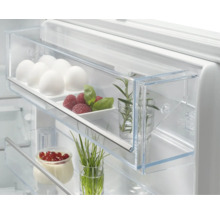 Interieur van een koelkast met eieren, frambozen, kruiden en yoghurt met rode bessen