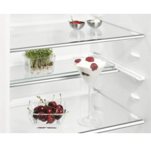 Kijkje in een koelkast met voedsel op glazen planken.