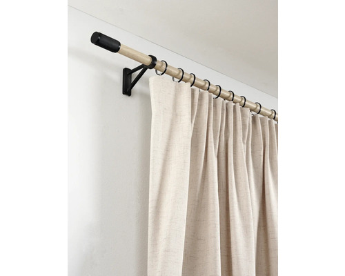 Houten gordijnroede met zwarte wandsteun, ringen en eindknop, voorzien van een beige gordijn met textuur.