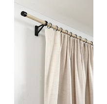 Gordijnroede van licht hout met zwarte metalen steunen en ringen, voorzien van een lichtbeige gordijn met linnenstructuur.