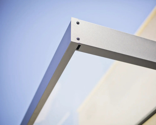 Detailopname van de hoekverbinding van een deurluifel met metalen frame en glaselement.