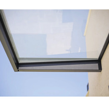 Moderne glazen deurluifel met antracietkleurig metalen frame aan een buitenmuur.