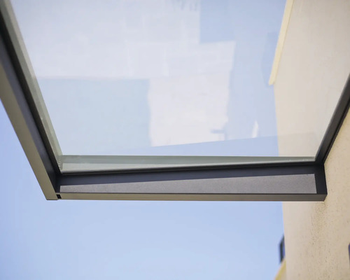 Moderne glazen deurluifel met antracietkleurig metalen frame aan een buitenmuur.