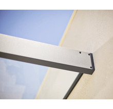 Muuraansluiting van een glazen luifelsteun van aluminium met zichtbare schroeven.