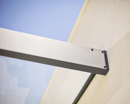 Muuraansluiting van een glazen luifelsteun van aluminium met zichtbare schroeven.