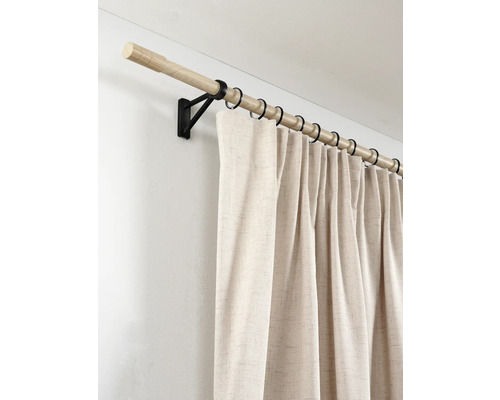Houten gordijnroede met zwarte wandsteun en ringen, voorzien van een lichtbeige gestructureerd gordijn.