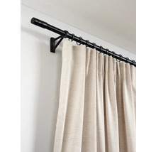 Zwarte metalen gordijnroede met ringen en beige gordijn van gestructureerde stof aan een muur gemonteerd.