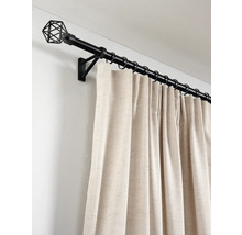 Zwarte metalen gordijnroede met geometrische draad eindknop, ringen en crèmekleurige gordijnen van gestructureerde stof aan de muur.
