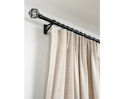 Zwarte metalen gordijnroede met geometrische draad eindknop, ringen en crèmekleurige gordijnen van gestructureerde stof aan de muur.