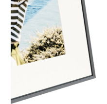 Detailopname van een zwarte fotolijst met een witte passe-partout en een foto.
