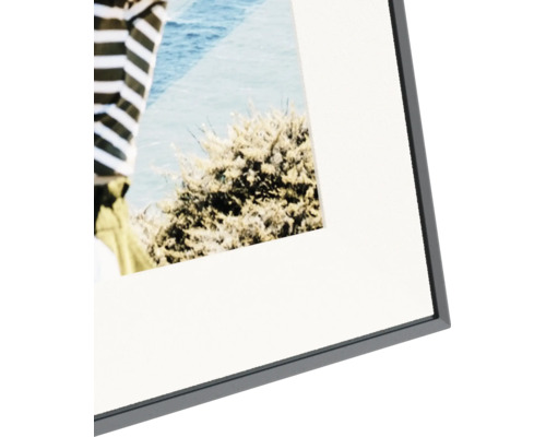Detailopname van een zwarte fotolijst met een witte passe-partout en een foto.