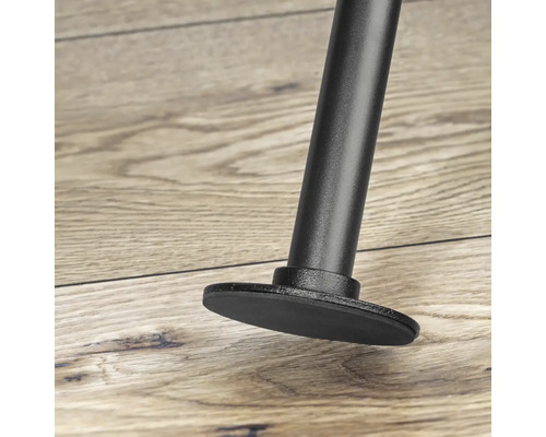 Detailopname van een zwarte meubelpoot met voet op een houten vloer.