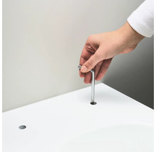 Een persoon steekt een inbussleutel in een gat in een wit oppervlak