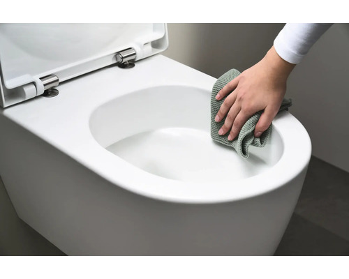Iemand maakt een wit hangtoilet schoon met een doek.