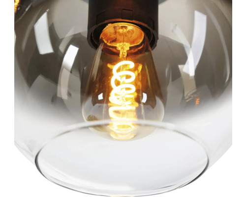 Close-up van een hanglamp met glazen behuizing en een gloeiende lichtbron.