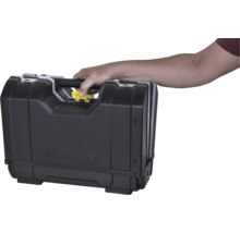 Hand draagt een Stanley gereedschapskoffer aan de handgreep en drukt op de gele ontgrendelknop.