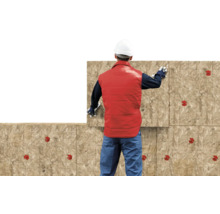 Bouwvakker installeert minerale wol isolatieplaten op een muur met rode isolatiepluggen.
