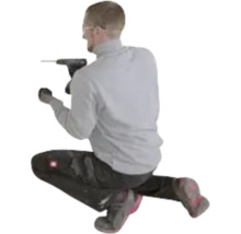 Een man in werkkleding knielt en werkt met een zwarte accuboorschroefmachine.
