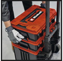 Einhell E-Case systeem gereedschapskoffers gestapeld op een trolley, vastgehouden door een hand met werkhandschoen.