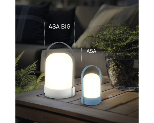Twee moderne LED-lantaarns ASA BIG en ASA op een houten tafel, sfeervolle buitenverlichting met planten en bank op de achtergrond.