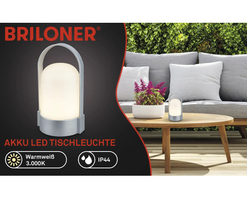 Briloner Logo, accu-led-tafellamp, warmwit 3000 kelvin, IP44 spatwaterdicht, draagbaar met handgreep, in de tuin op een houten tafel.