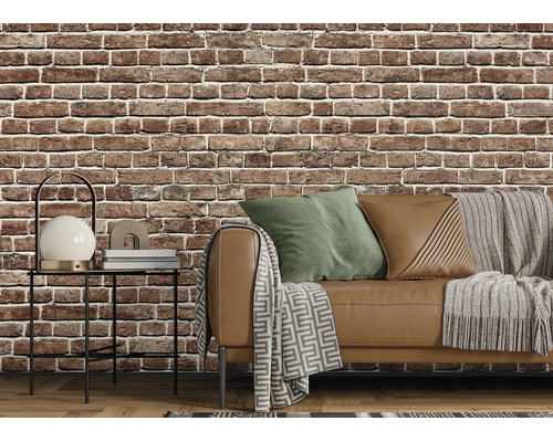 Vliesbehang met baksteenmotief in een woonkamer in industriële stijl met bank, bijzettafel en textiel.