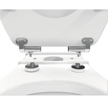 Detailopname van de verchroomde metalen scharnieren voor de bevestiging van een toiletzitting op een wit toilet.