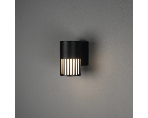 Cilindrische buitenwandlamp in zwart met verticale lichtsleuven en warm licht.