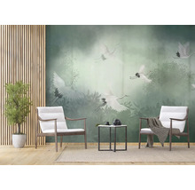 Fotobehang met witte kraanvogels boven een groen nevelwoud in een modern ingerichte woonkamer met houten fauteuils en bijzettafel.