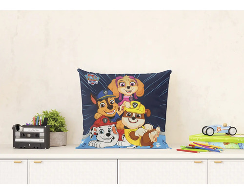 Lichte en georganiseerde scène met een vierkant Paw Patrol sierkussen met Marshall, Chase, Rubble en Skye op een bureau.