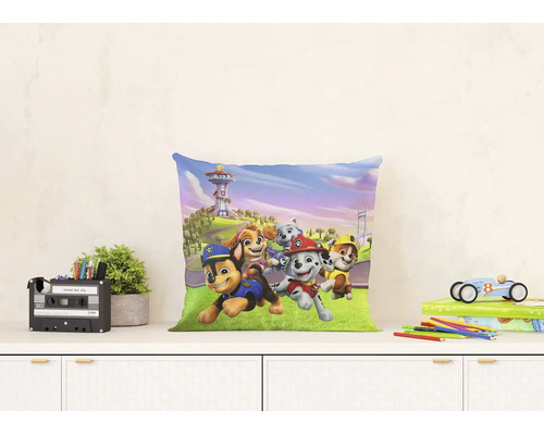 Vierkant sierkussen met Paw Patrol motief op een dressoir naast een plant en speelgoed.