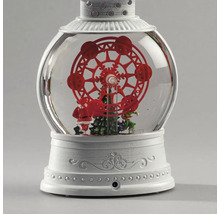Decoratieve sneeuwbollantaarn met een rood reuzenrad, kerstboom en kerstmanfiguur op een witte, bewerkte voet.