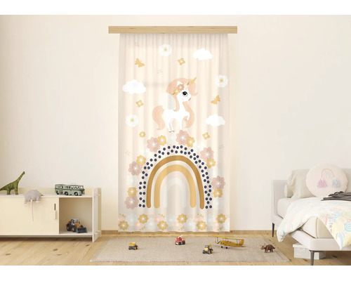 Gordijn voor de kinderkamer met eenhoorn- en regenboogmotief in een lichte, georganiseerde kamer met speelgoed en een bed.