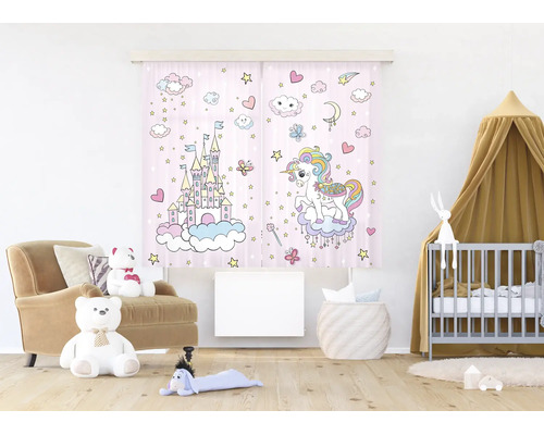 Tweedelig gordijn voor de kinderkamer met eenhoorn- en kasteelmotief in een lichte, georganiseerde kinderkamer met fauteuil en babybed.
