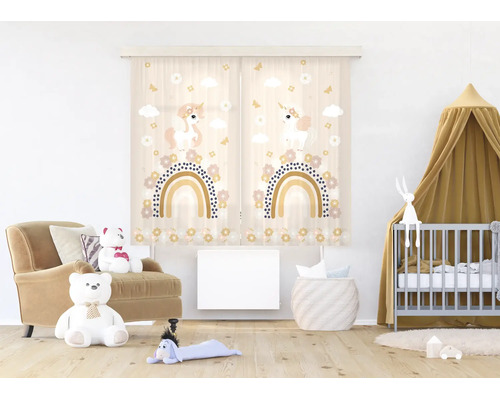 Lichte babykamer met gordijnen met eenhoorn- en regenboogmotief, een babybedje met hemeltje, een fauteuil met teddyberen en een radiator.
