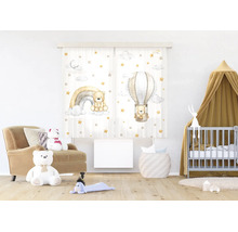 Lichte kinderkamer met gordijnen met teddybeer-motieven, een regenboog en luchtballon, een fauteuil, een babybedje en een houten vloer.