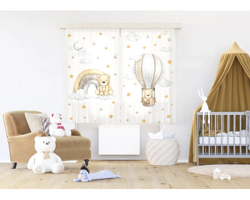 Lichte kinderkamer met gordijnen met teddybeer-motieven, een regenboog en luchtballon, een fauteuil, een babybedje en een houten vloer.