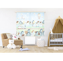 Paneelgordijn met landschapsmotief van trein en luchtballon in lichte kinderkamer met babybed en fauteuil.
