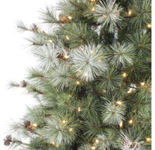 Kunstkerstboom met warmwitte LED-verlichting, dennenappels en besneeuwde naalden in detail.