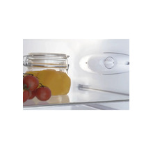 Binnenaanzicht van een koelkast met glazen plateau, weckpot, tomaten en een mechanische thermostaatknop.