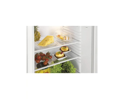 Open koelkast met glazen plateaus, gevuld met verse etenswaren zoals kaas, tomaten, fruitgebakjes en sla.