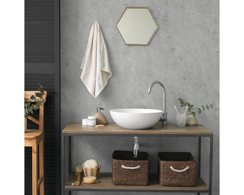Moderne badkamer met ronde opzetwastafel, hoge kraan en een wastafelmeubel van hout en metaal. Boven de wastafel hangt een zeshoekige spiegel.