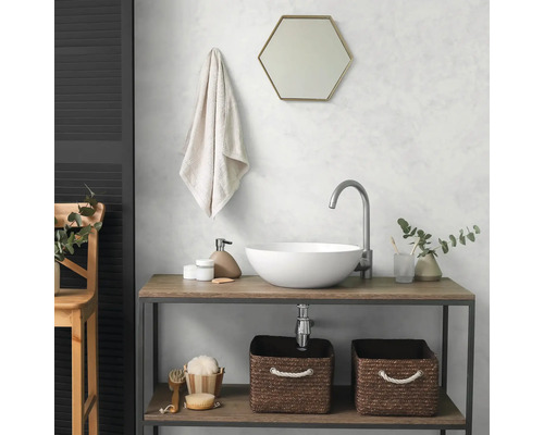 Moderne badkamer met witte opzetwastafel op houten meubel, hoge kraan, zeshoekige spiegel en gevlochten manden.
