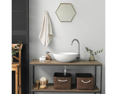 Moderne badkamer met witte opzetwastafel, hoge kraan, zeshoekige spiegel en houten wastafelmeubel met opbergmanden.