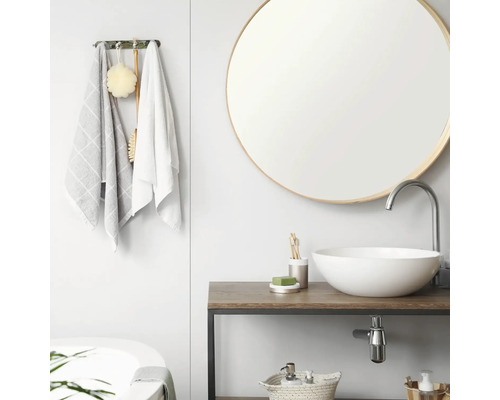 Moderne, lichte badkamer met ronde spiegel, witte opzetwastafel op houten wastafelblad en handdoekhouder met textiel.
