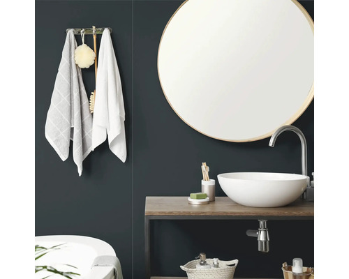 Moderne badkamer met een ronde wandspiegel, een witte opzetwastafel op een houten blad en handdoekhouder.
