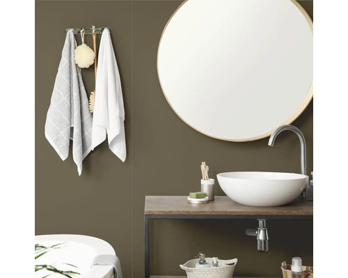 Moderne badkamer met olijfgroene muur, ronde spiegel met houten lijst, witte opzetwastafel op een houten wastafelmeubel en handdoeken.